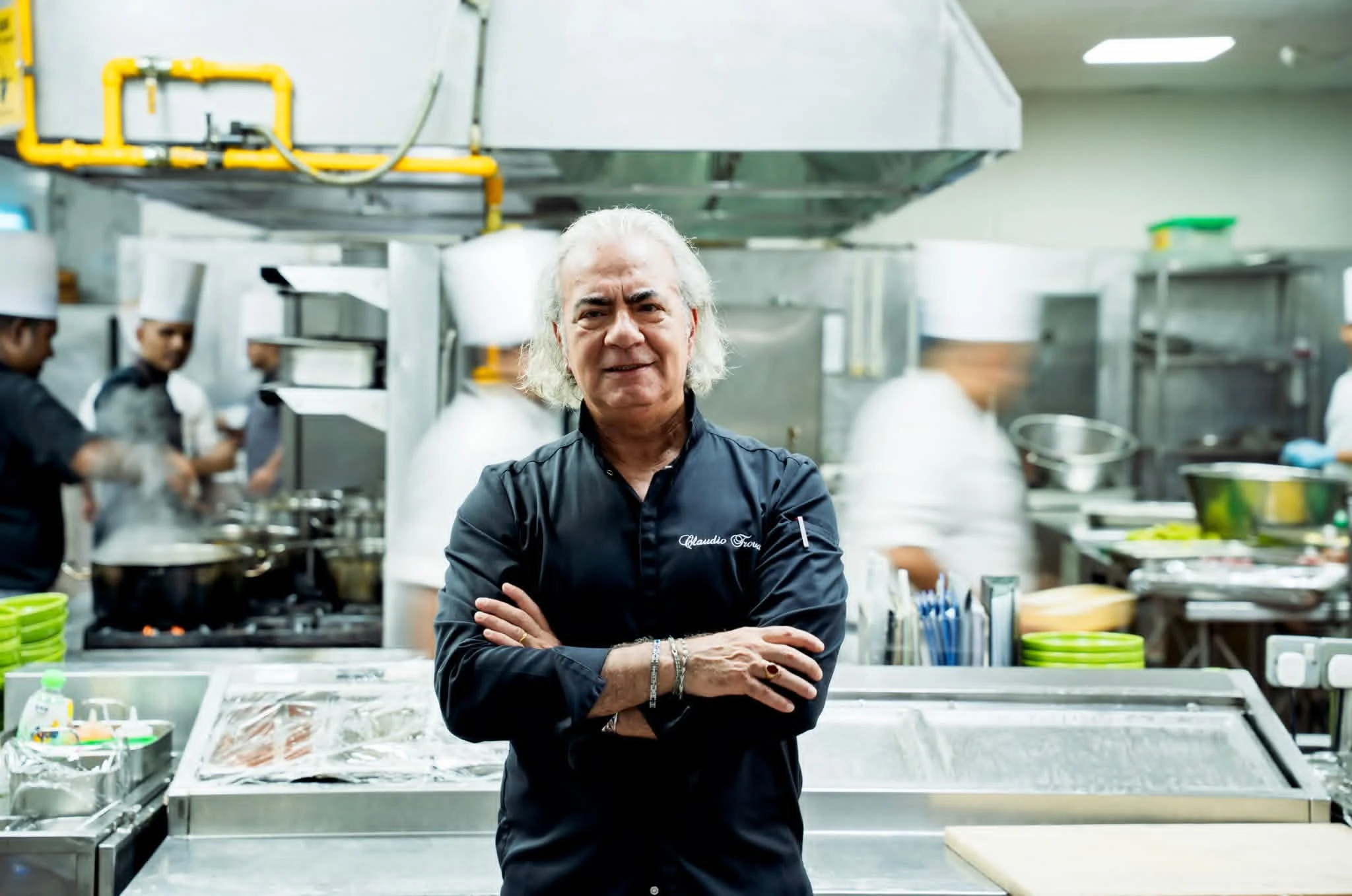 Claudio Trovato a braccia conserte nella sua cucina, con la brigata al lavoro