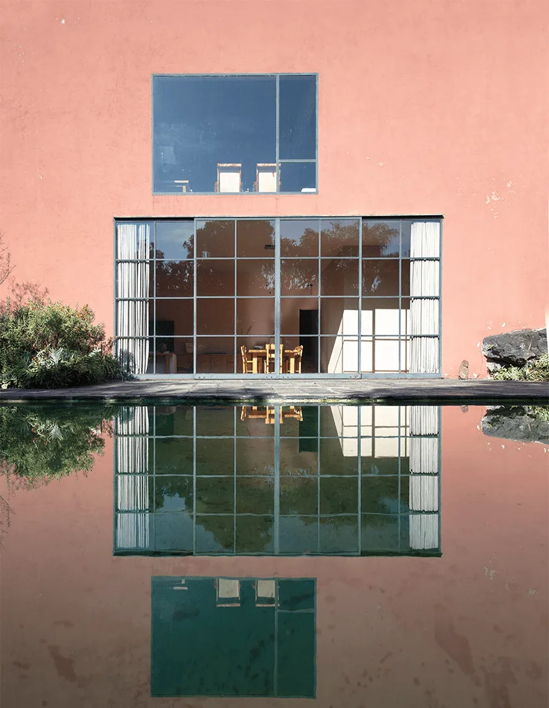 Casa Pedregal di Luis Barragán: la parete rosa e la grande vetrata riflesse nello specchio d'acqua.