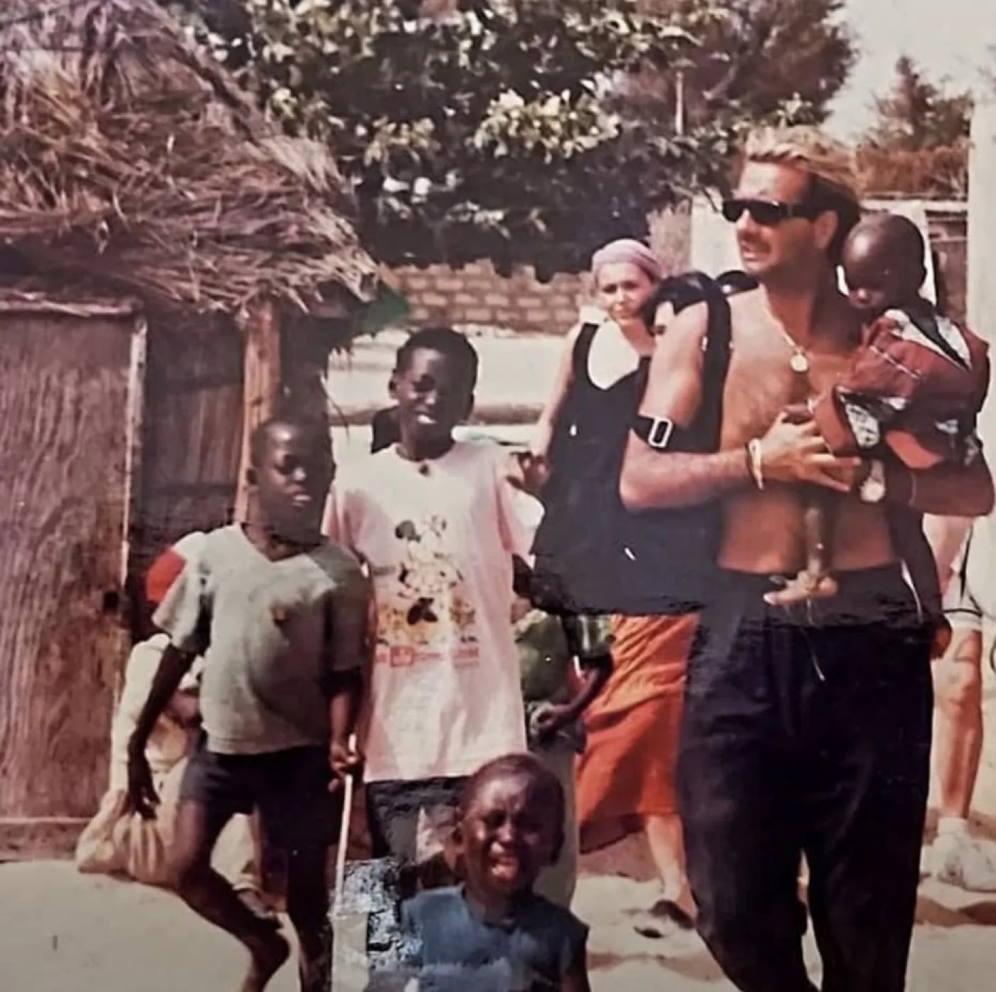 Lo chef, giovane, con un bimbo sulle spalle in un villaggio africano.